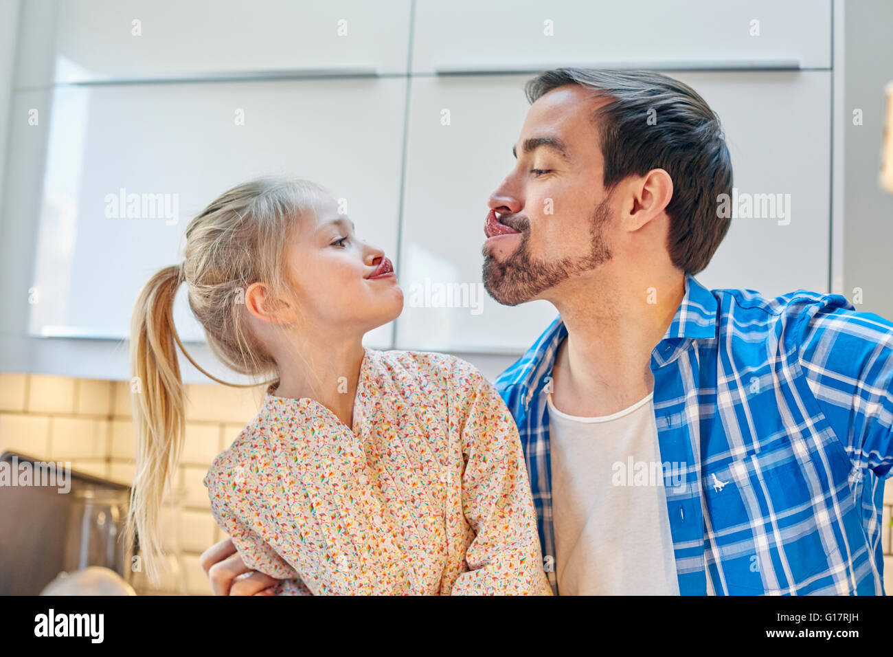 Father and daughter taking selfie of funny face in kitchen Stock Photo