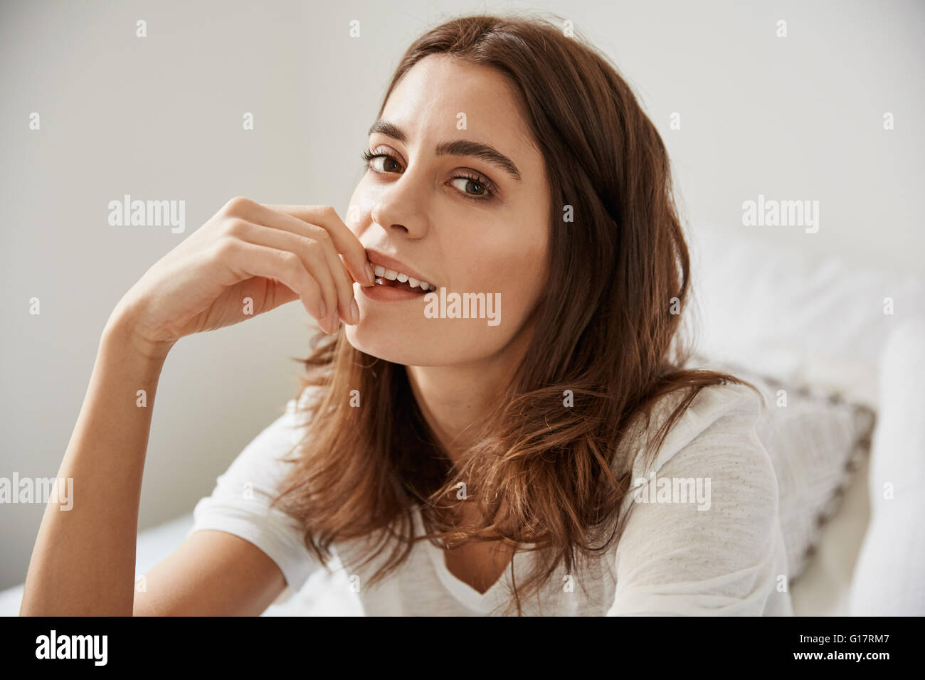 Portrait of beautiful young woman sitting on bed Stock Photo - Alamy