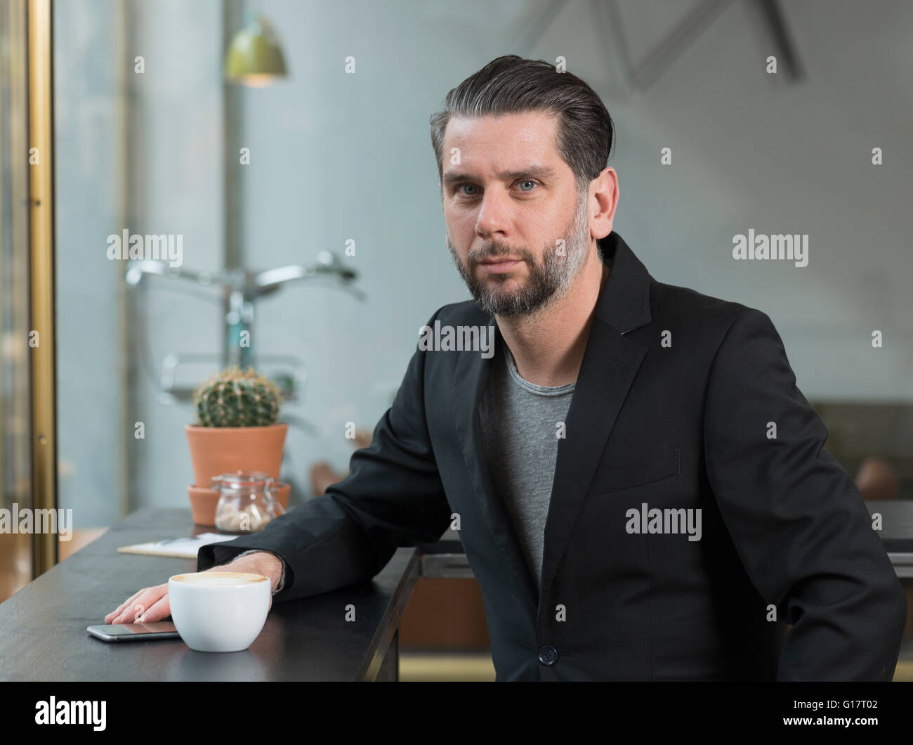 Portrait of cool businessman sitting at cafe window seat Stock Photo