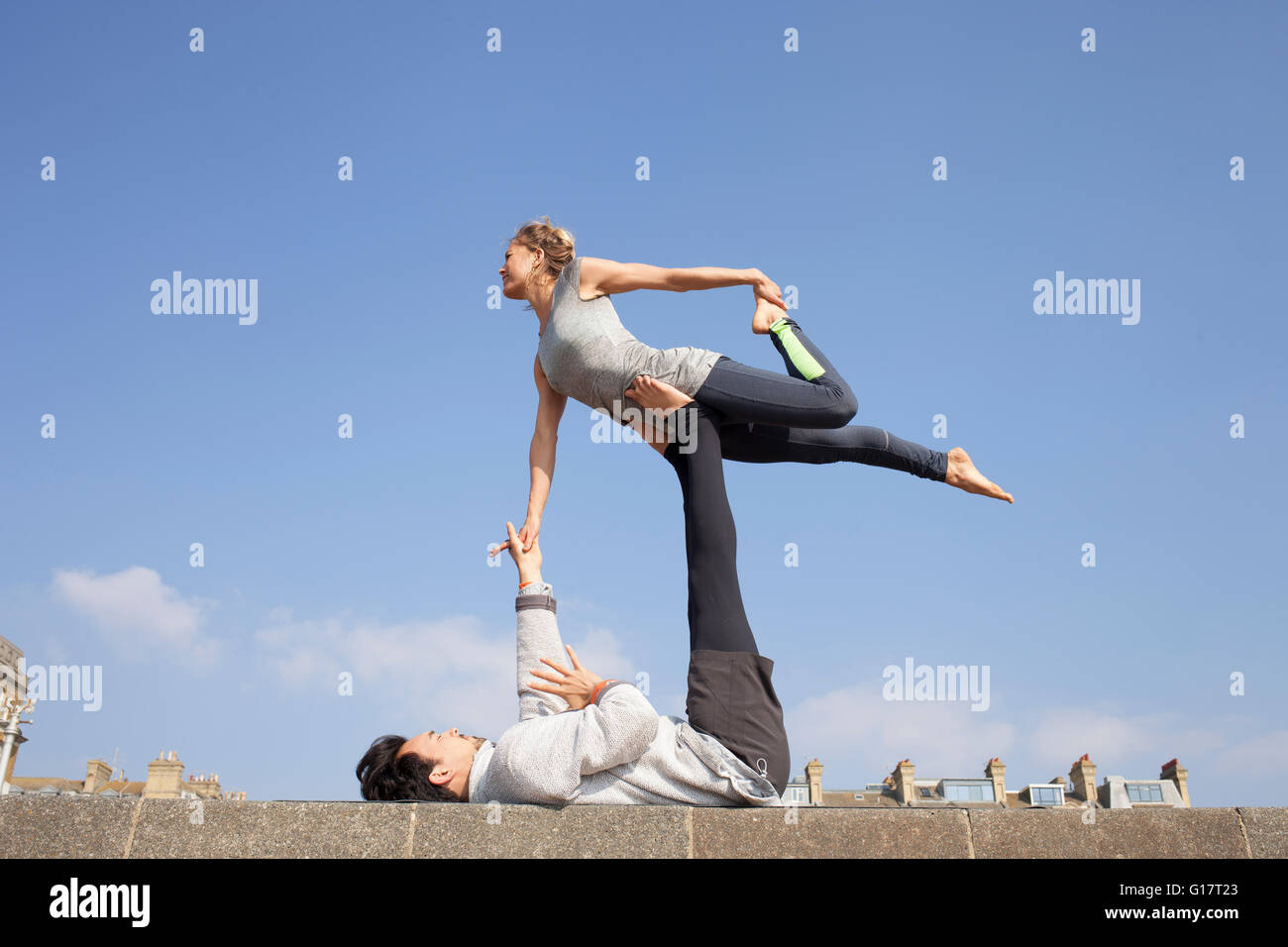 Man and woman practicing acrobatic yoga on wall Stock Photo