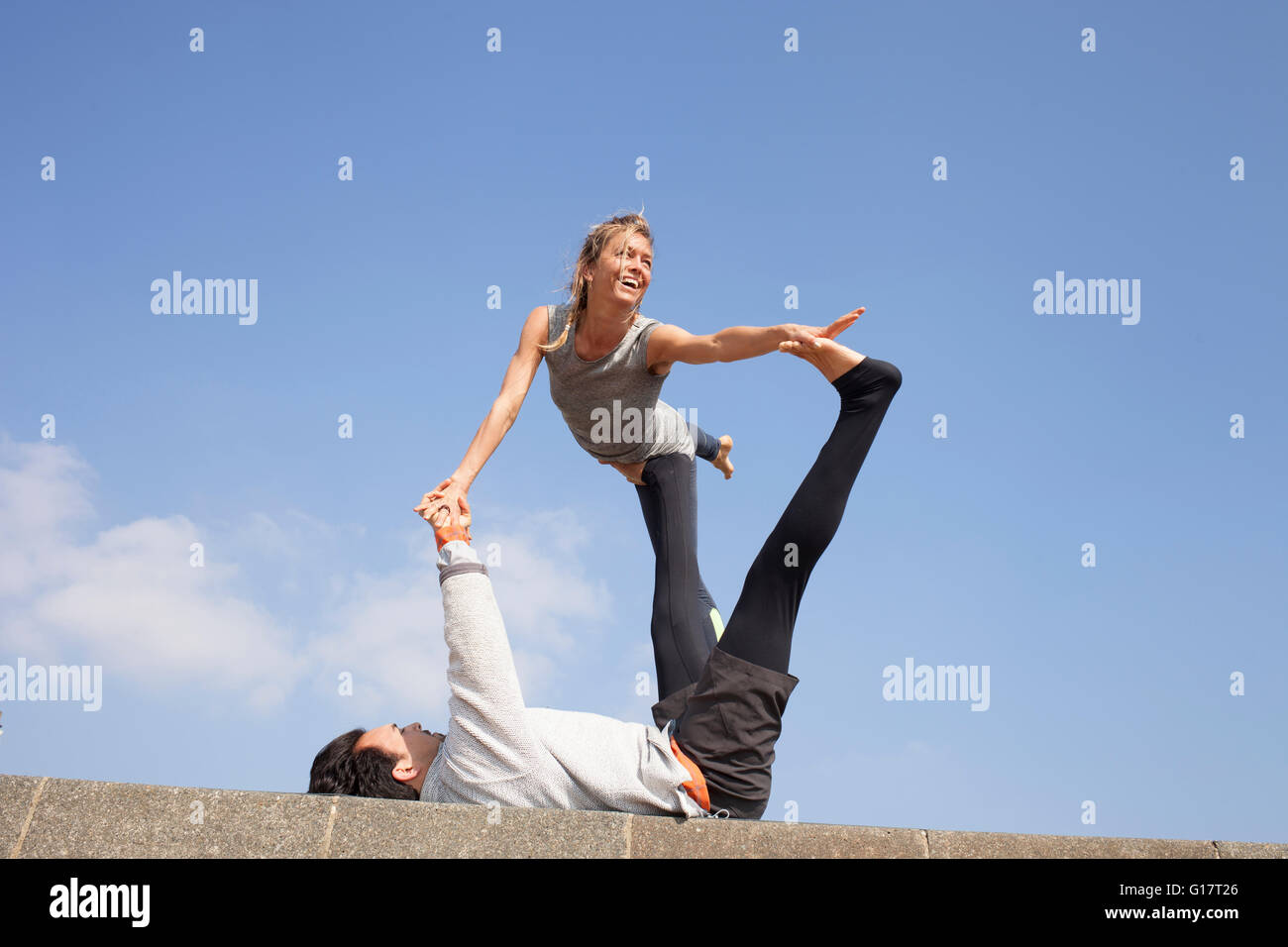 Man and woman on wall practicing acrobatic yoga Stock Photo