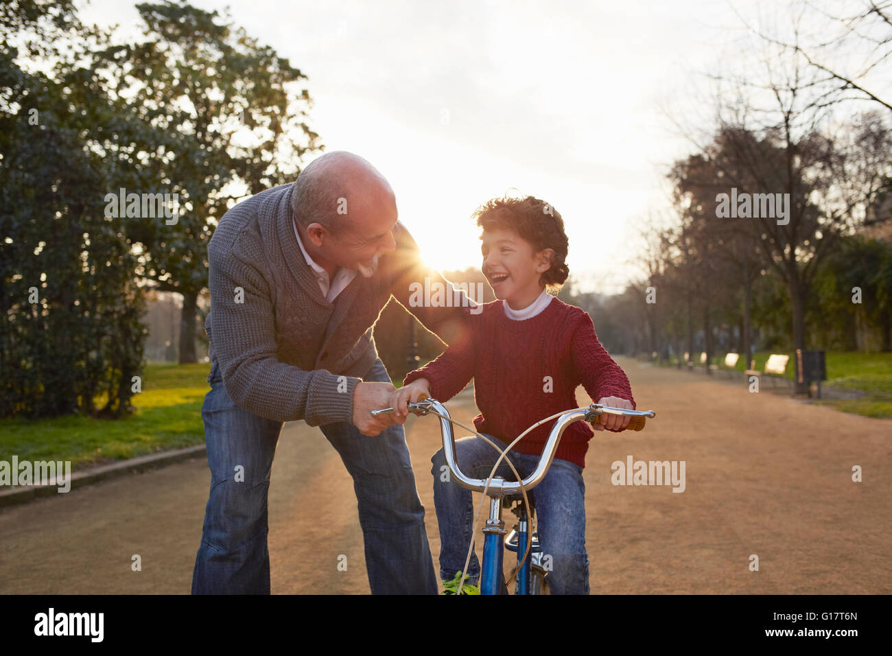 Grandfather teaching grandson to ride bicycle in park Stock Photo