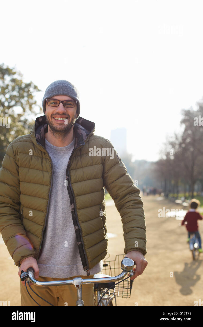 Man wearing knit hat and glasses holding bicycle looking at camera smiling Stock Photo