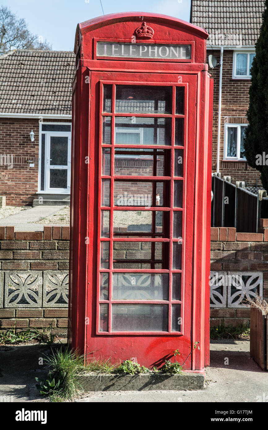 An old red phone box with broken glass and missing panels. Stock Photo