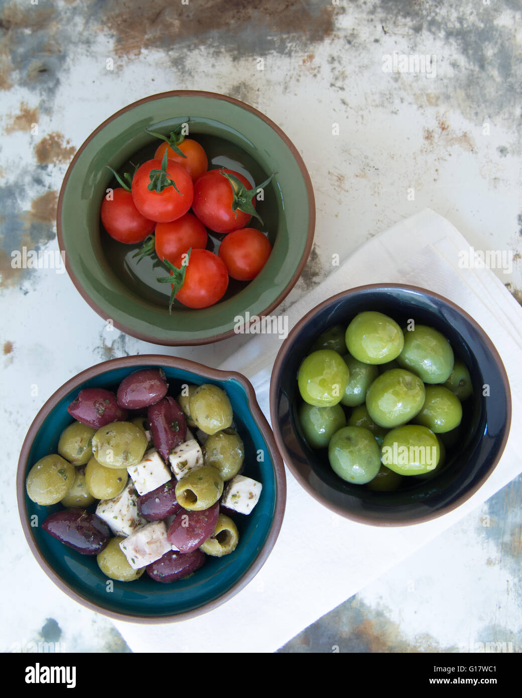 hors d'Oeuvres - overhead view of small bowls of olives, feta and cherry tomatoes against rustic background Stock Photo