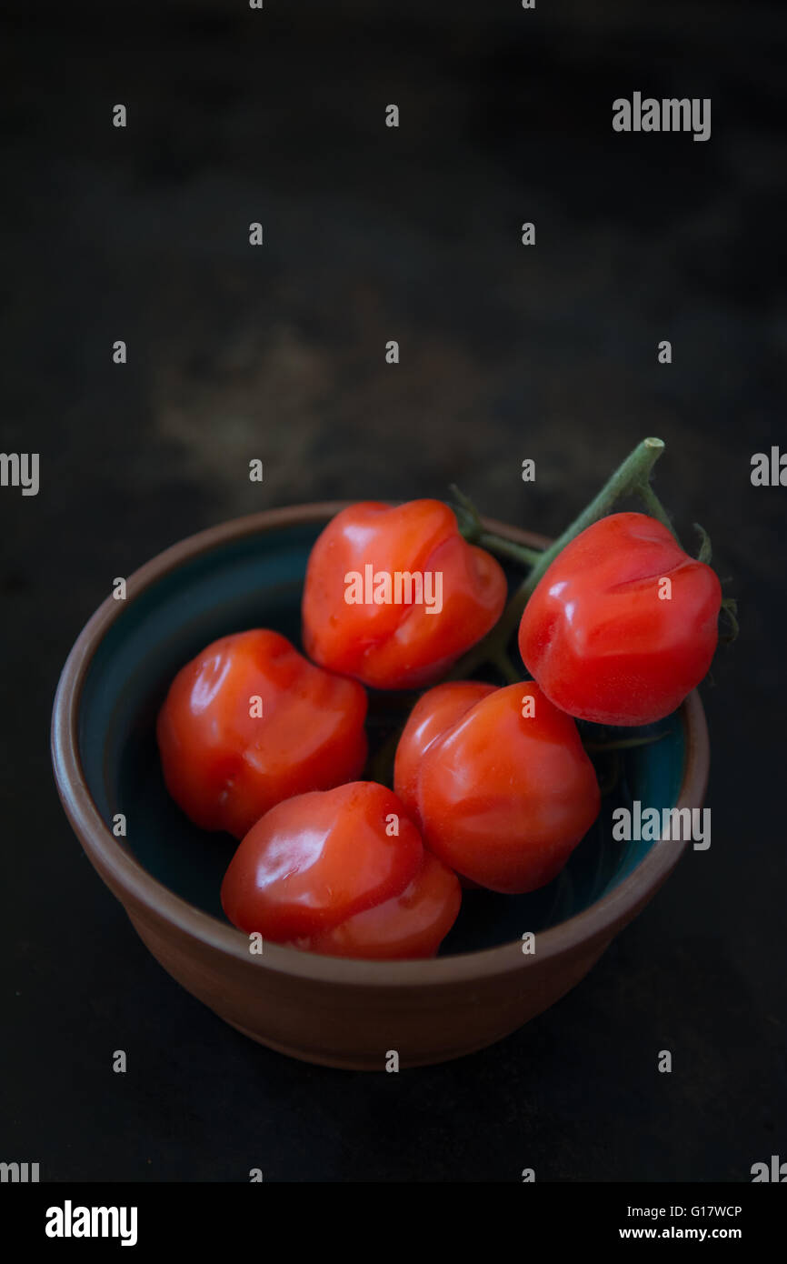 tomatoes in small bowl with dark background Stock Photo