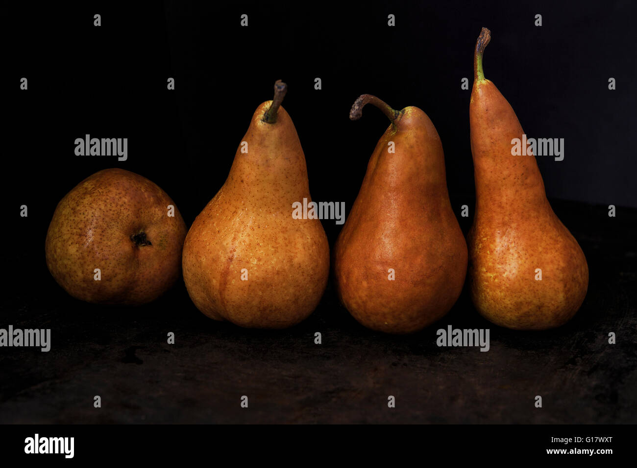 https://c8.alamy.com/comp/G17WXT/four-golden-brown-pears-with-little-tails-on-a-black-background-G17WXT.jpg