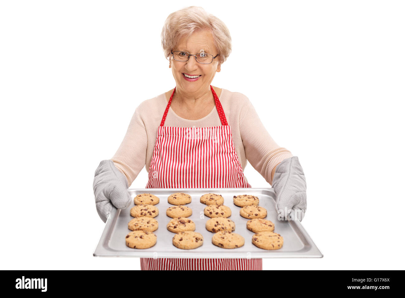 Mature lady handing a tray full of chocolate chip cookies and smiling isolated on white background Stock Photo