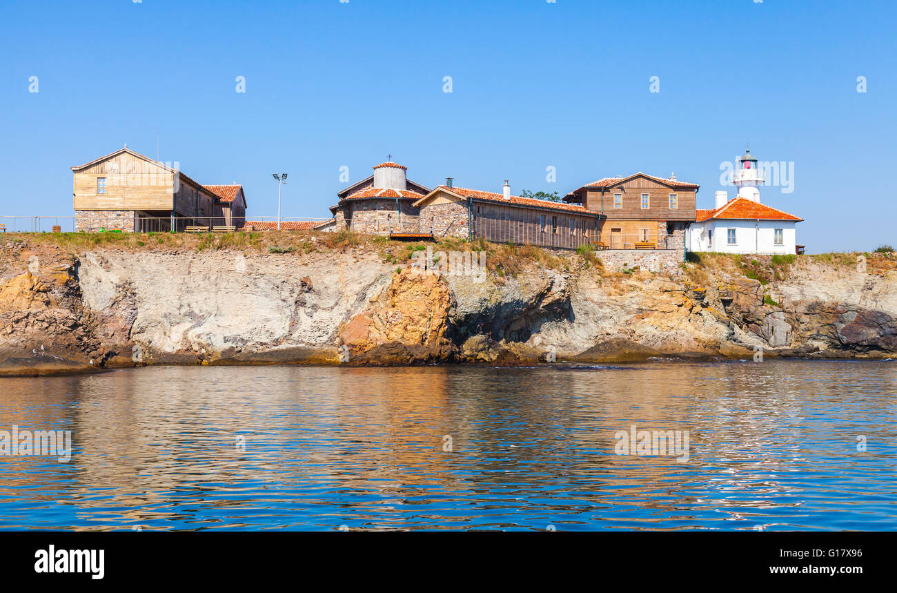 St Anastasia Island. Burgas bay, Black Sea, Bulgaria. White lighthouse tower and old wooden buildings on rocky coast Stock Photo