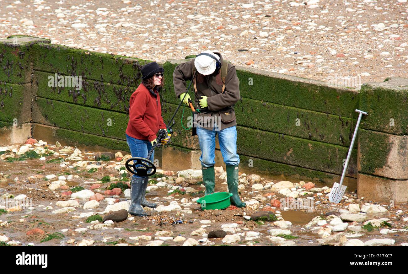 A couple searching for treasure using a metal detector on Hunstanton beach Norfolk England UK Stock Photo