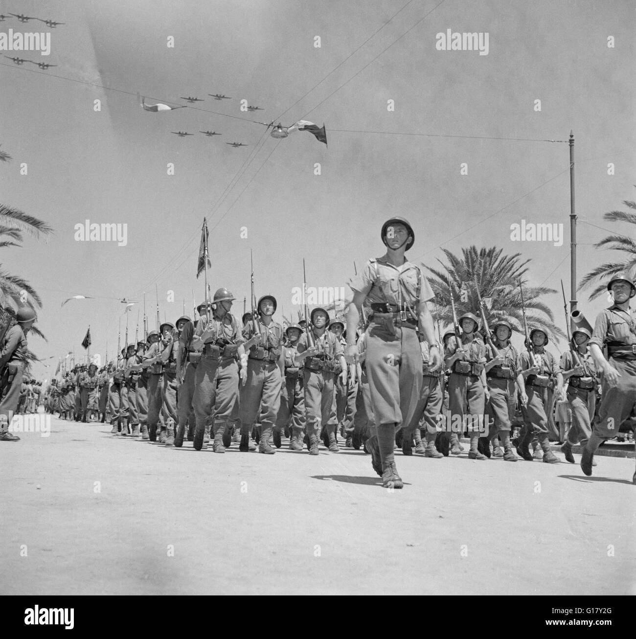 French Troops Passing Reviewing Stand in Allied Victory Parade along Avenue Gambetta as American Planes Fly Overhead in Show of Allied Might, Tunis, Tunisia, Marjorie Collins for Office of War Information, May 20, 1943 Stock Photo