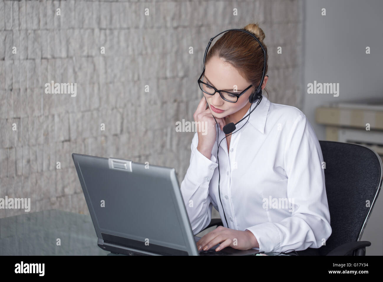 Female customer support emloyee talking online in office Stock Photo