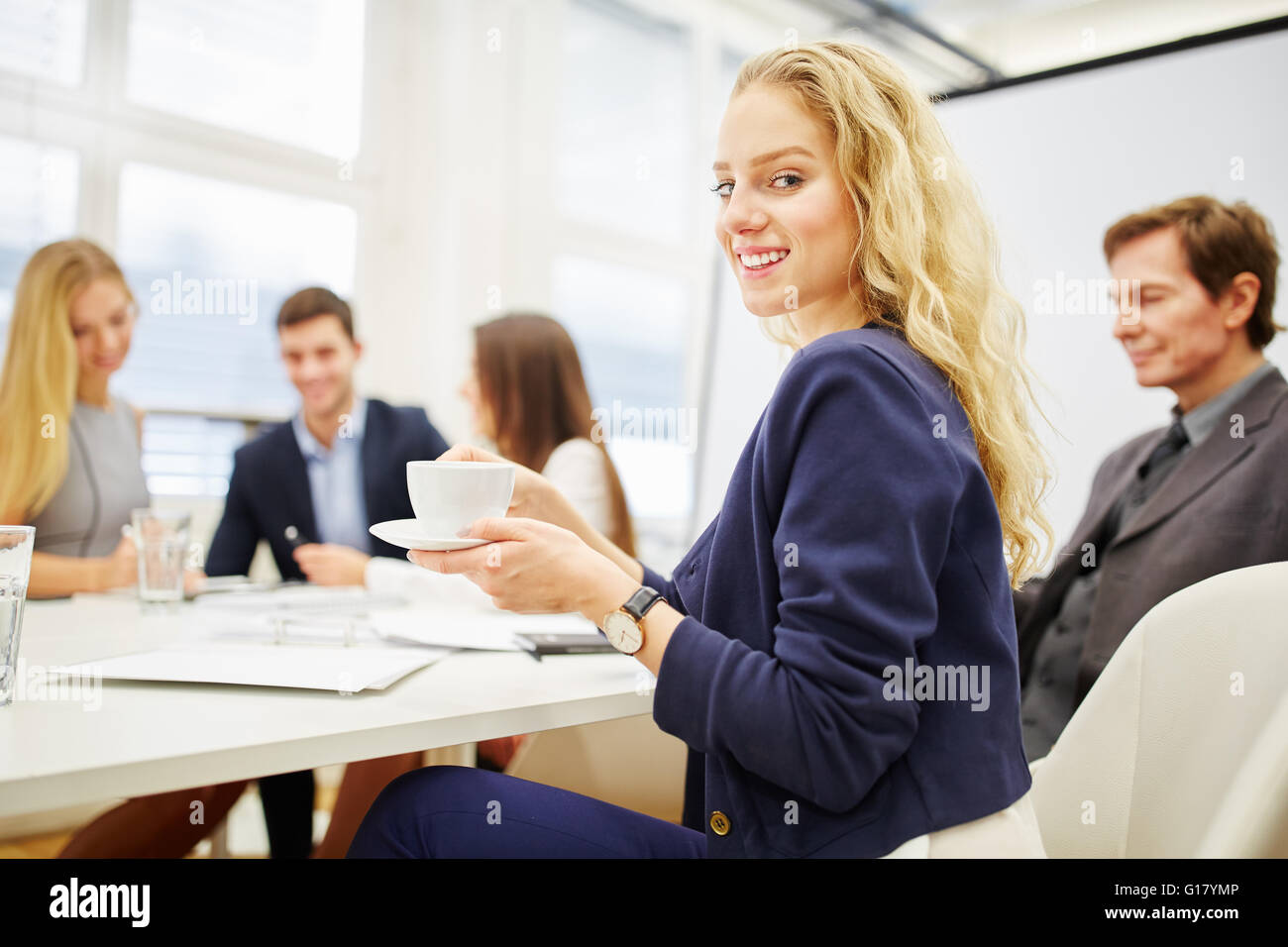 Young businesswoman drinking coffee in a business meeting Stock Photo