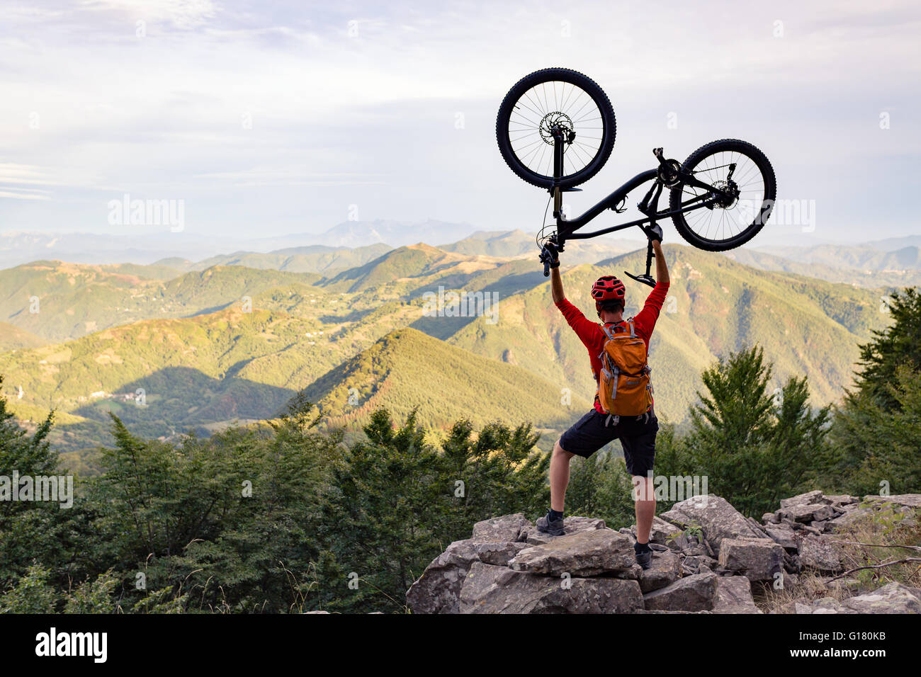Mountain biker success, looking at view celebrating with bike up on