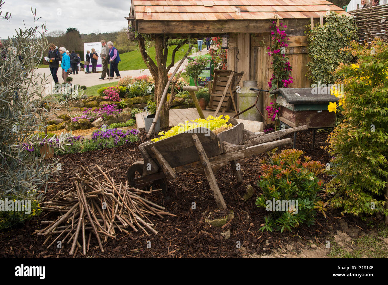 Visitors to Harrogate Spring Flower Show 2016 (North Yorkshire, England) pass a rustic shed and natural planting in 'Wildlife Paradise' show garden. Stock Photo