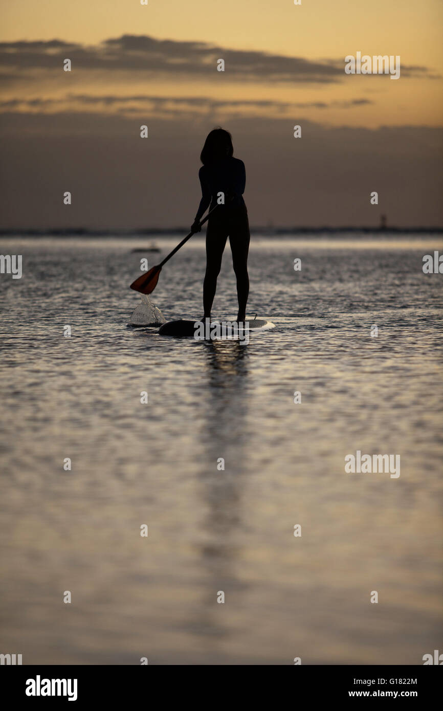 Woman leisurely paddling stand up board at Ala Moana Beach Park at