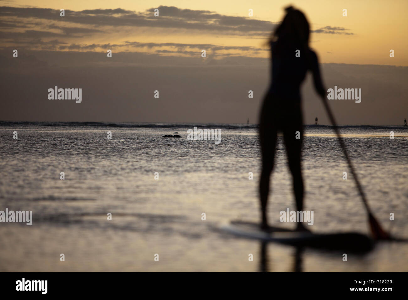 Woman leisurely paddling stand up board at Ala Moana Beach Park at