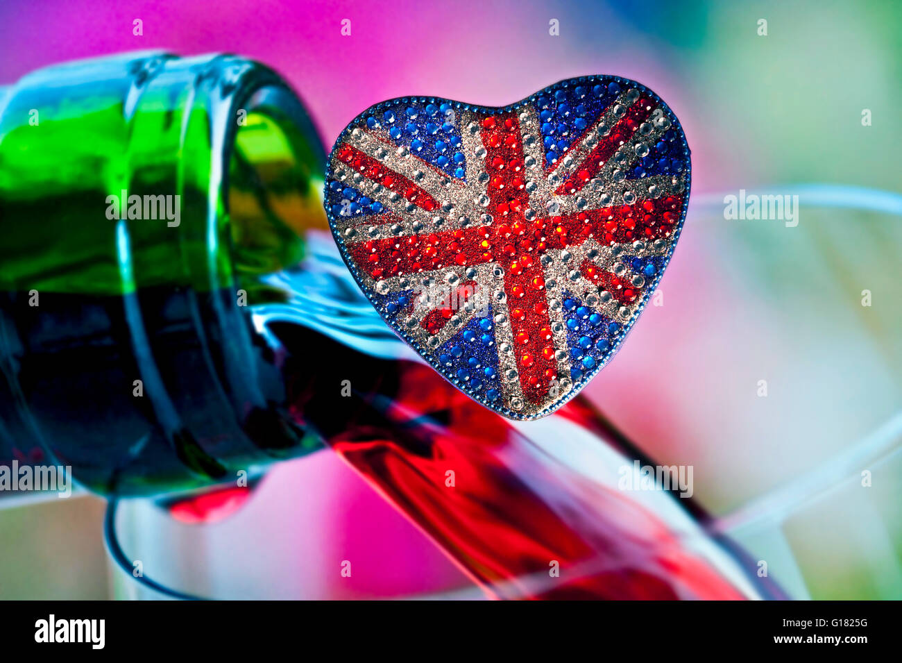 English wine concept with love heart shaped reflective sparkling Union Jack Flag motif & colorful wine bottle pouring behind Stock Photo
