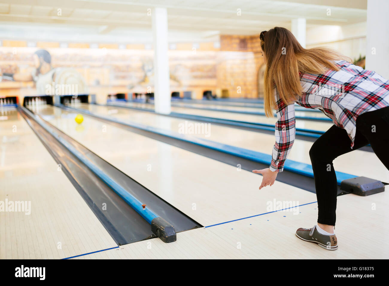 Woman throwing bowling ball in club Stock Photo