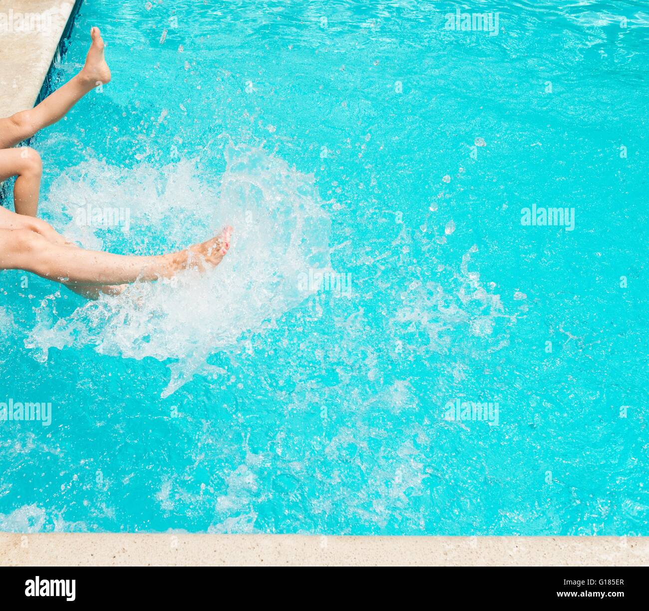 Legs splashing water in swimming pool Stock Photo