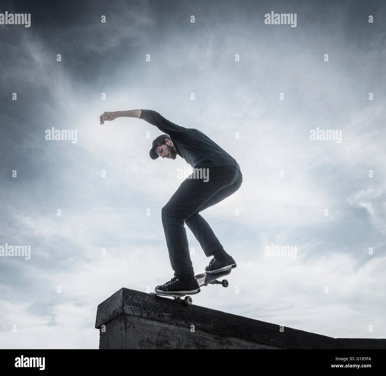 Young man skateboarding on roof Stock Photo