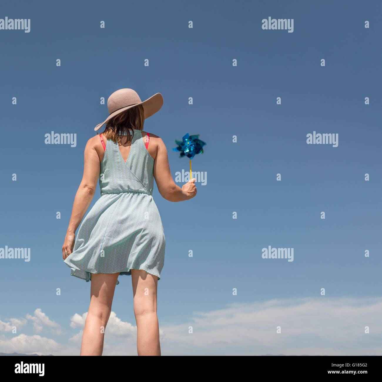 Rear view of woman with hat holding paper windmill Stock Photo