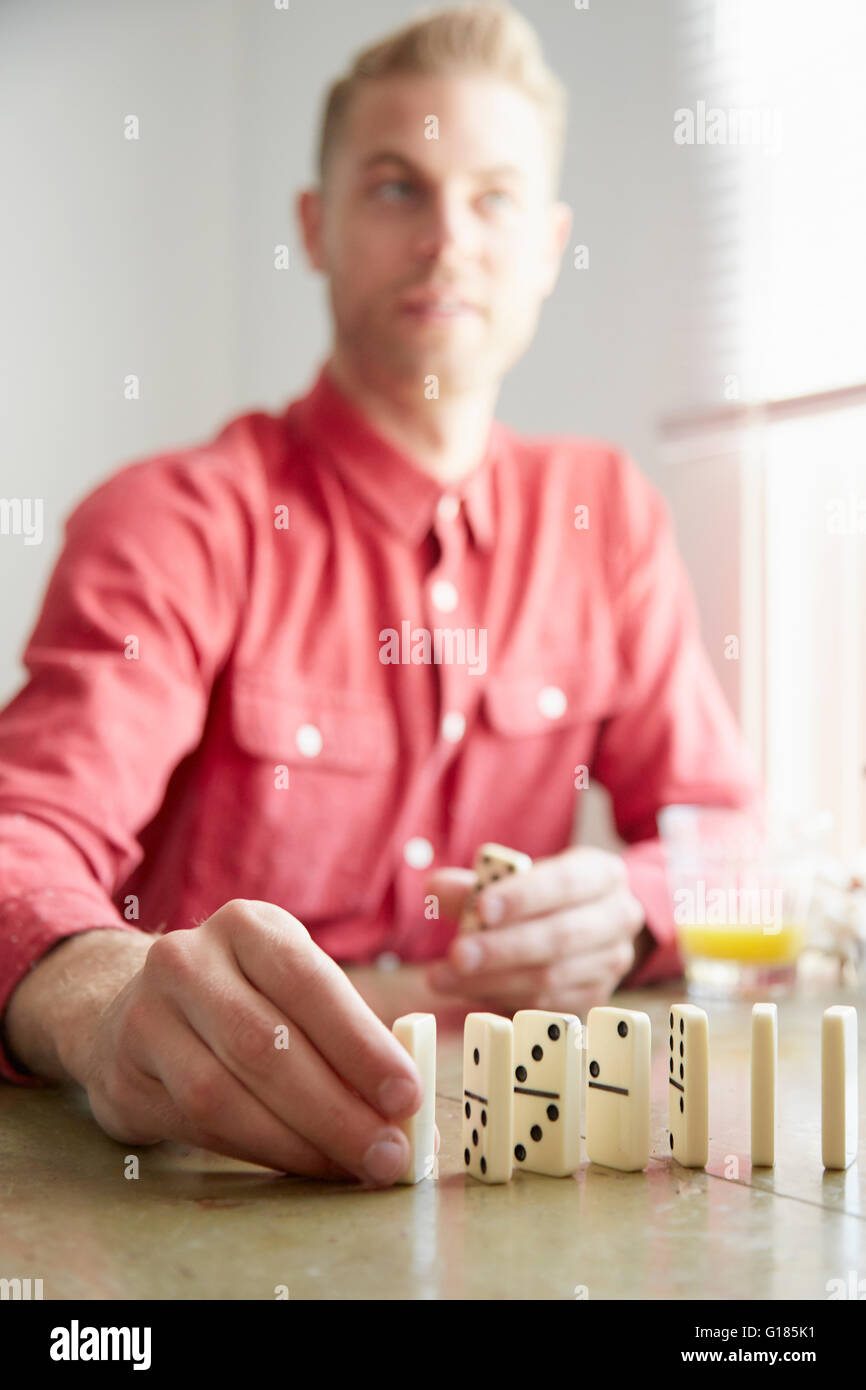 Man placing domino on edge Stock Photo