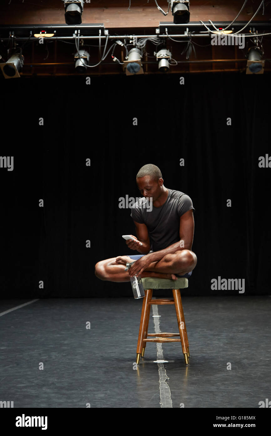 Dancer sitting on stool texting Stock Photo