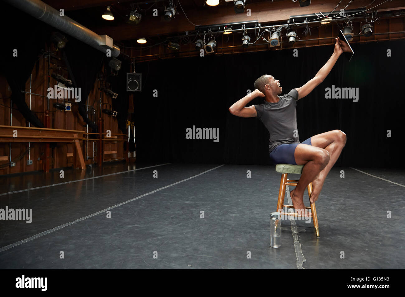 Dancer sitting on stool taking selfie with digital tablet Stock Photo