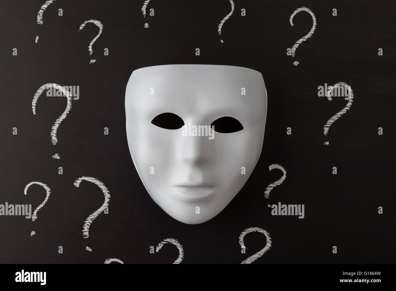 White mask on black background with hand drawn chalk question marks. Who am I ? Identity concept. Horizontal image. Stock Photo