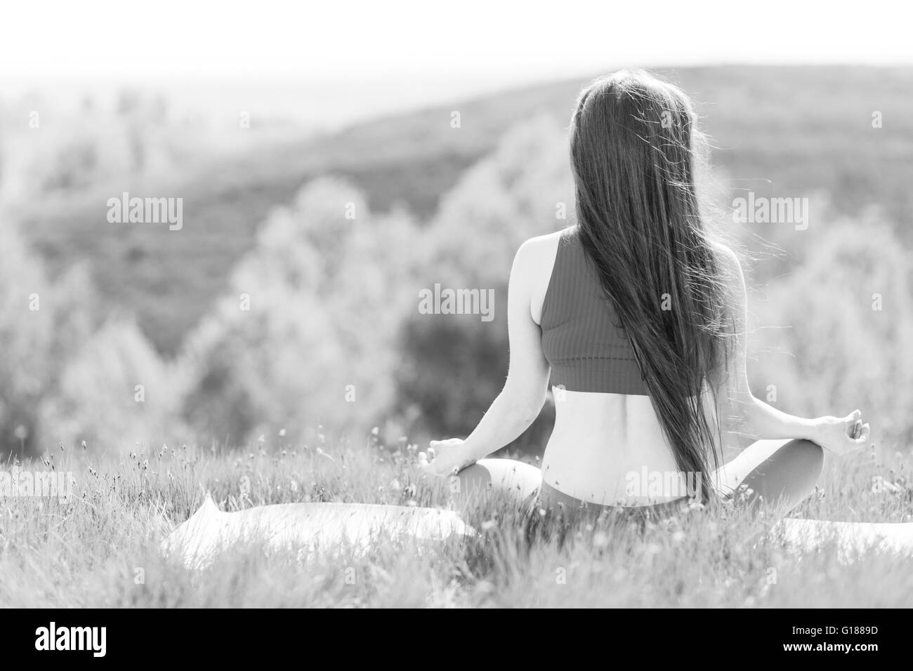 Young woman doing yoga lotus pose outdoors in the morning. Black and white image of relaxing Stock Photo