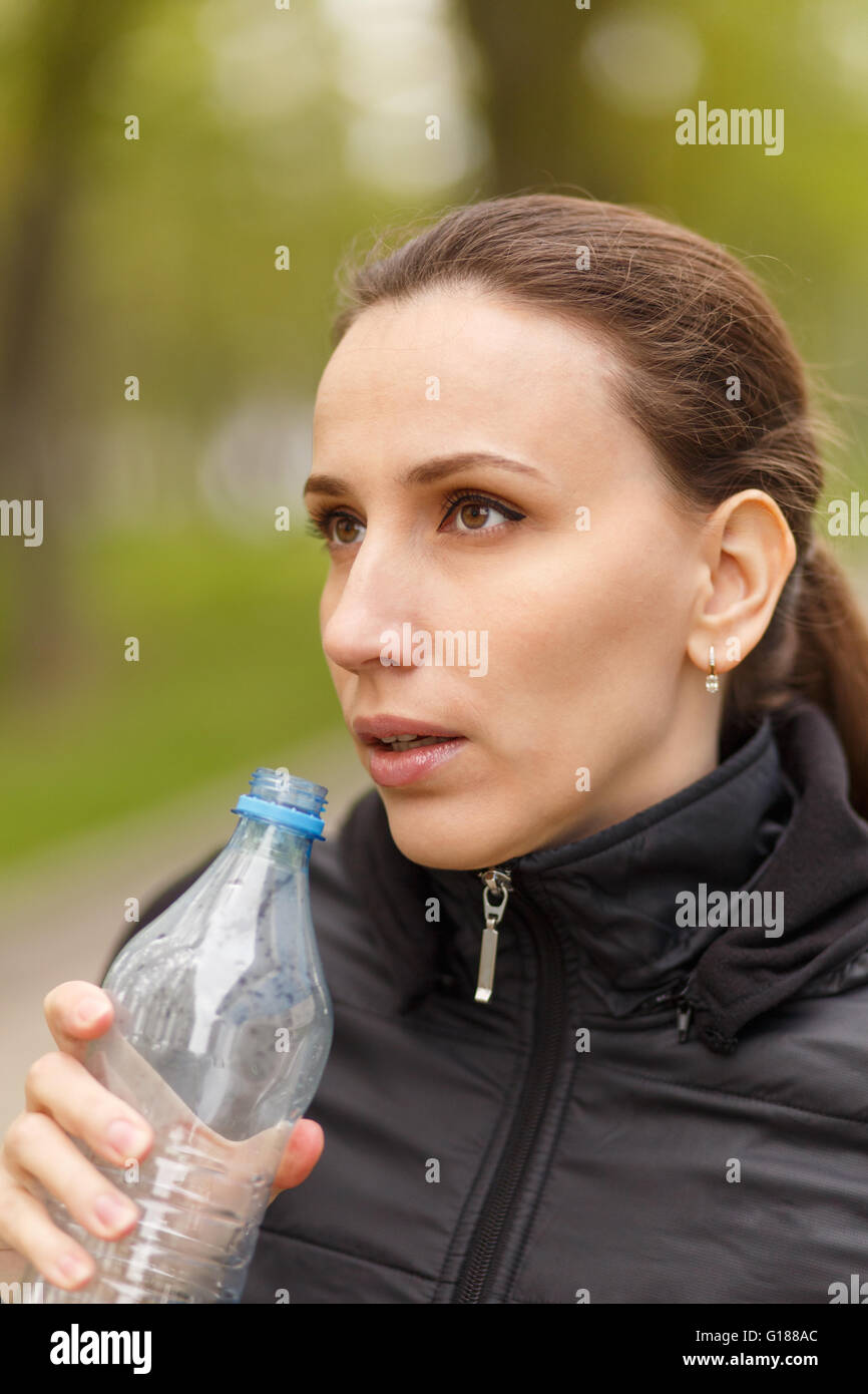 Young woman drinking water after workout jogging. Caucasian girl