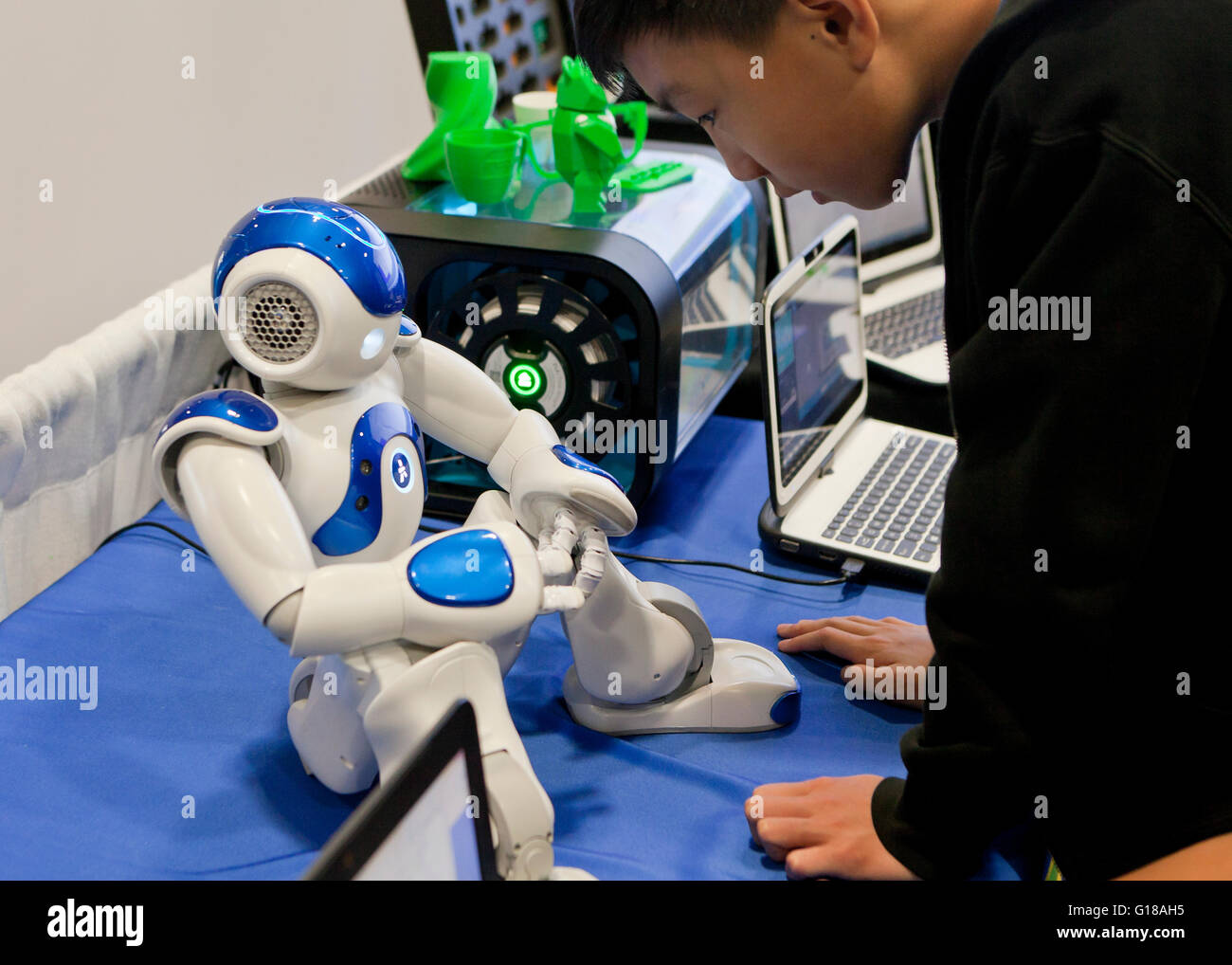 Child interacting with humanoid robot at a science and engineering fair - USA Stock Photo