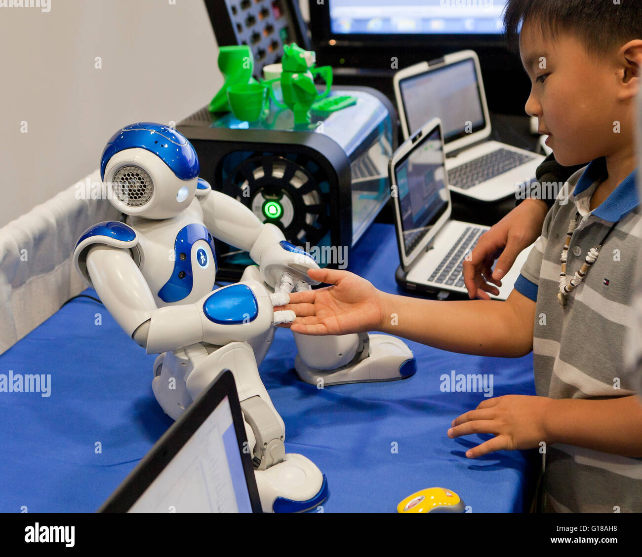 Child interacting with humanoid robot at a science and engineering fair - USA Stock Photo