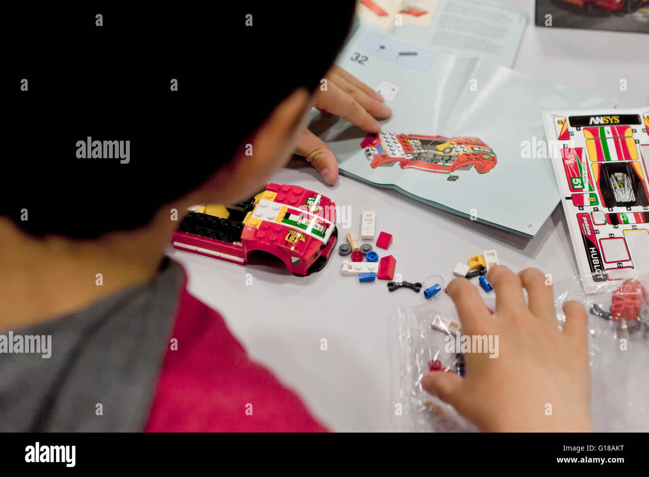 Child building a Lego sports car using the instruction manual - USA Stock Photo