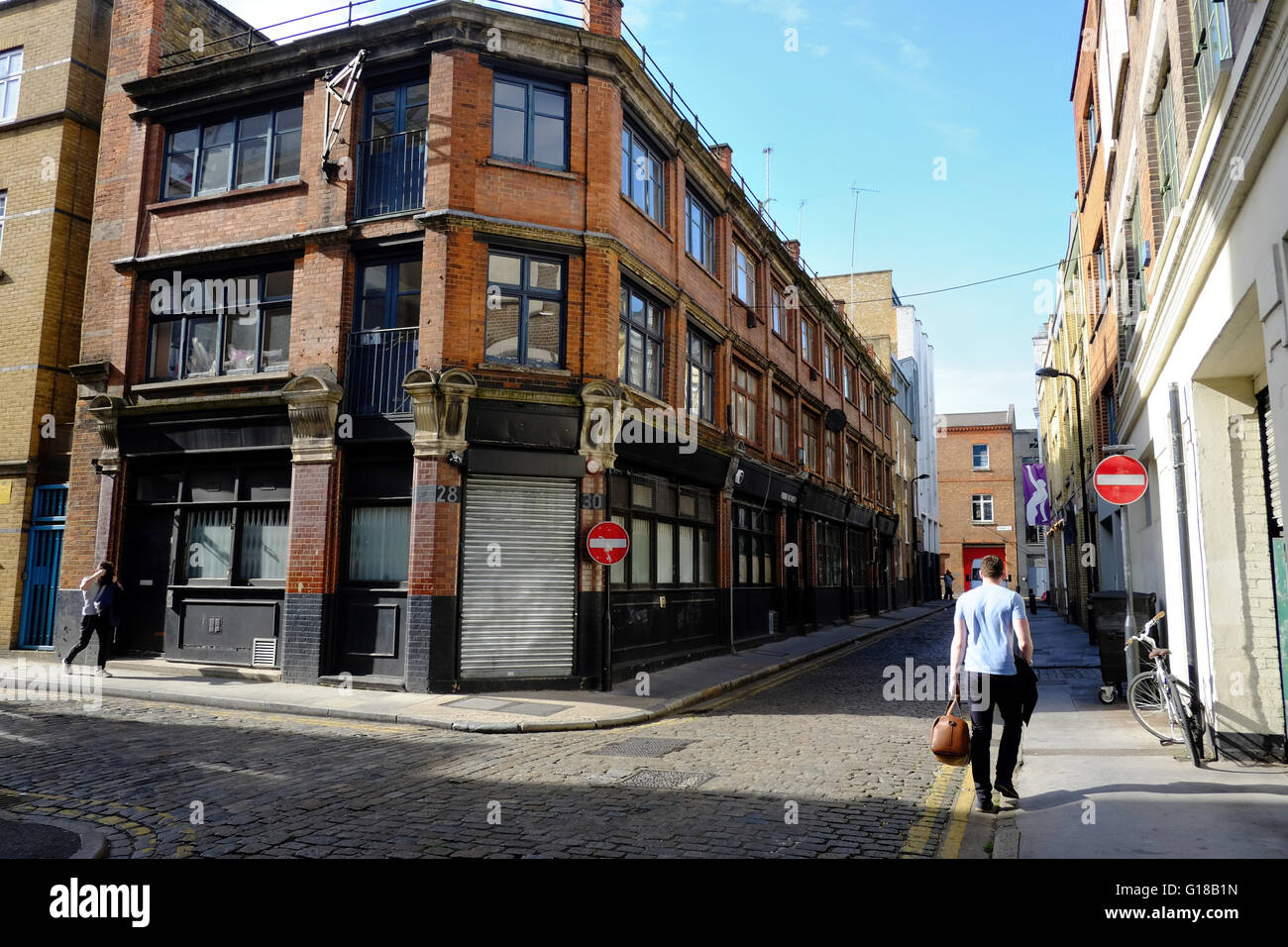 A man walks down a quiet cobbled streets in East London Stock Photo