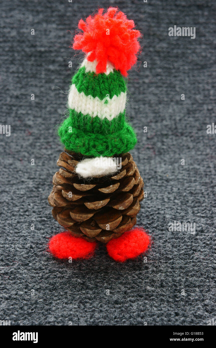 Christmas pine gnome, pinecone wear Xmas hat for decoration on winter holiday, red, green yarn, homemade product by knitted hat Stock Photo