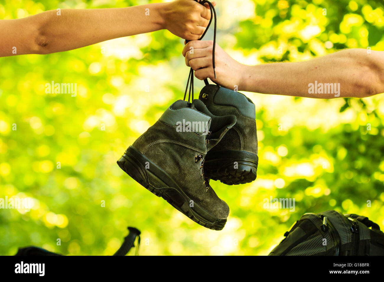 Nature outdoor hiking trip travel holidays outdoor footwear concept. Two people pass boots. One person passes shoes to another one. Stock Photo