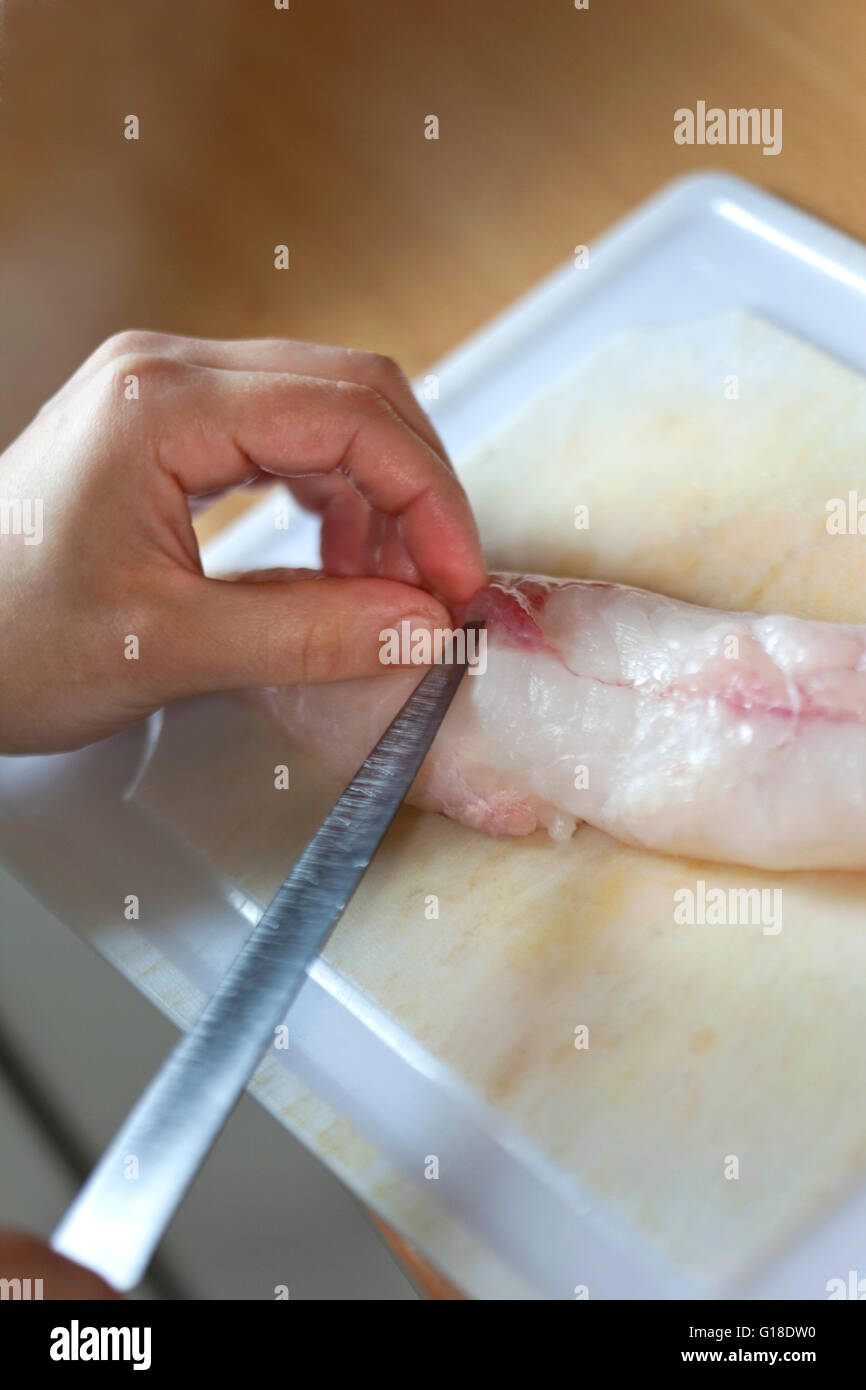 Cook cutting a monk-fish fillet in a kitchen Stock Photo