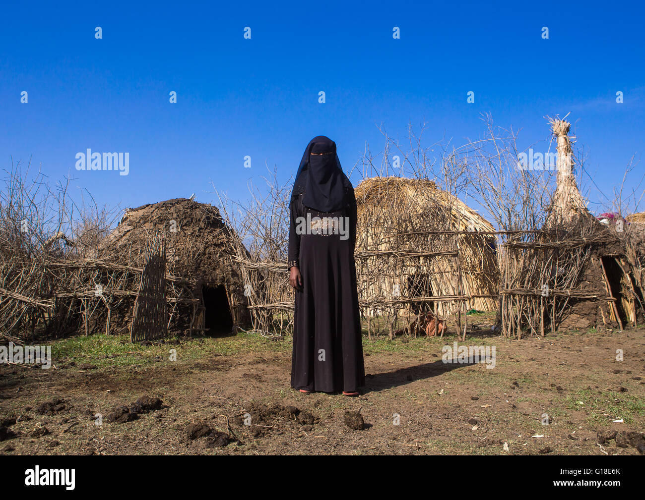An ethiopian oromo woman dressed in black burqa stands in front of her hut, Amhara region, Artuma, Ethiopia Stock Photo