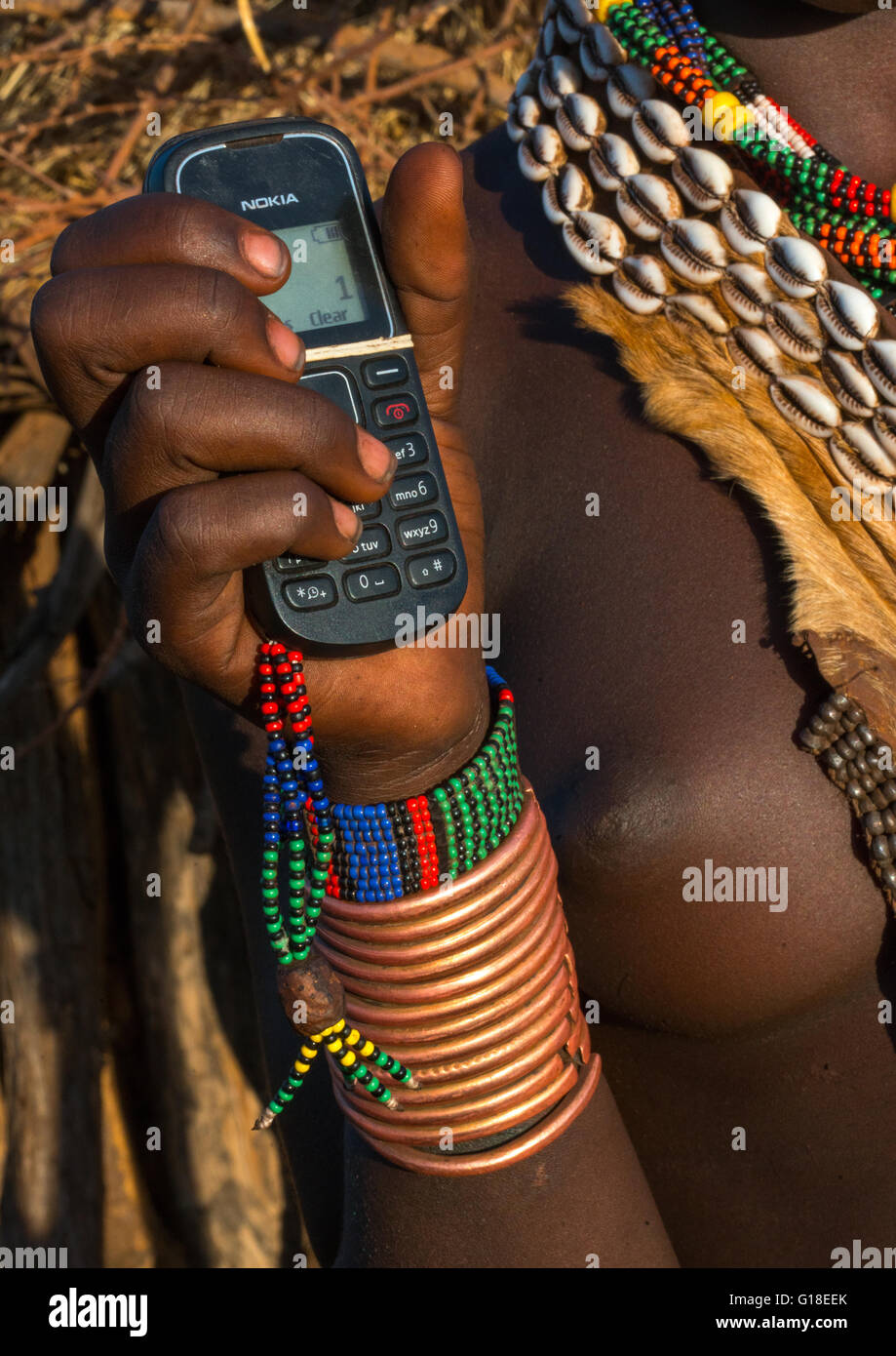 Hamer tribe girl with brass bracelets holding a nokia mobile phone, Omo valley, Turmi, Ethiopia Stock Photo