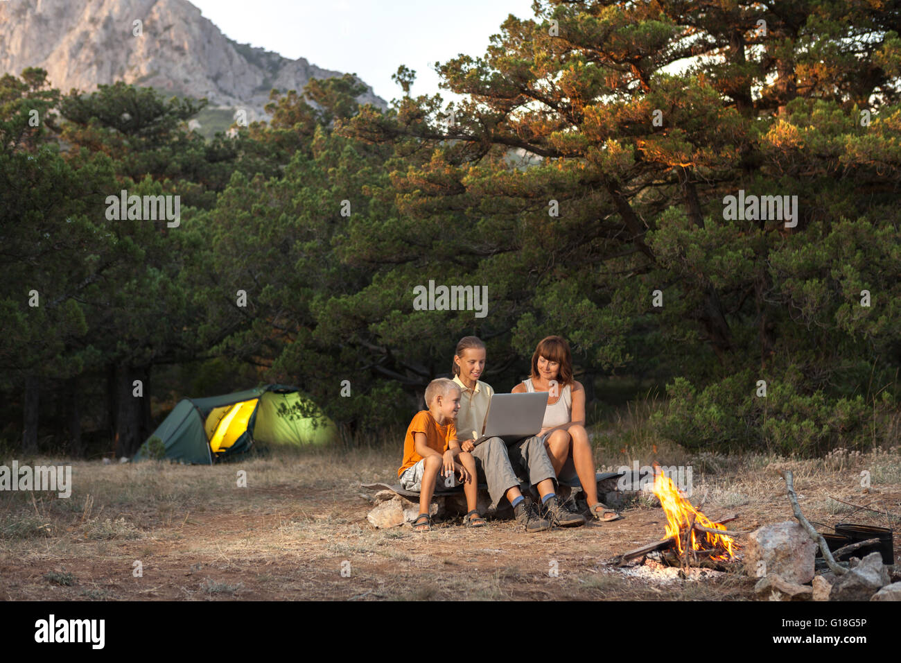 Family of trhee people with laptop at the camping Stock Photo