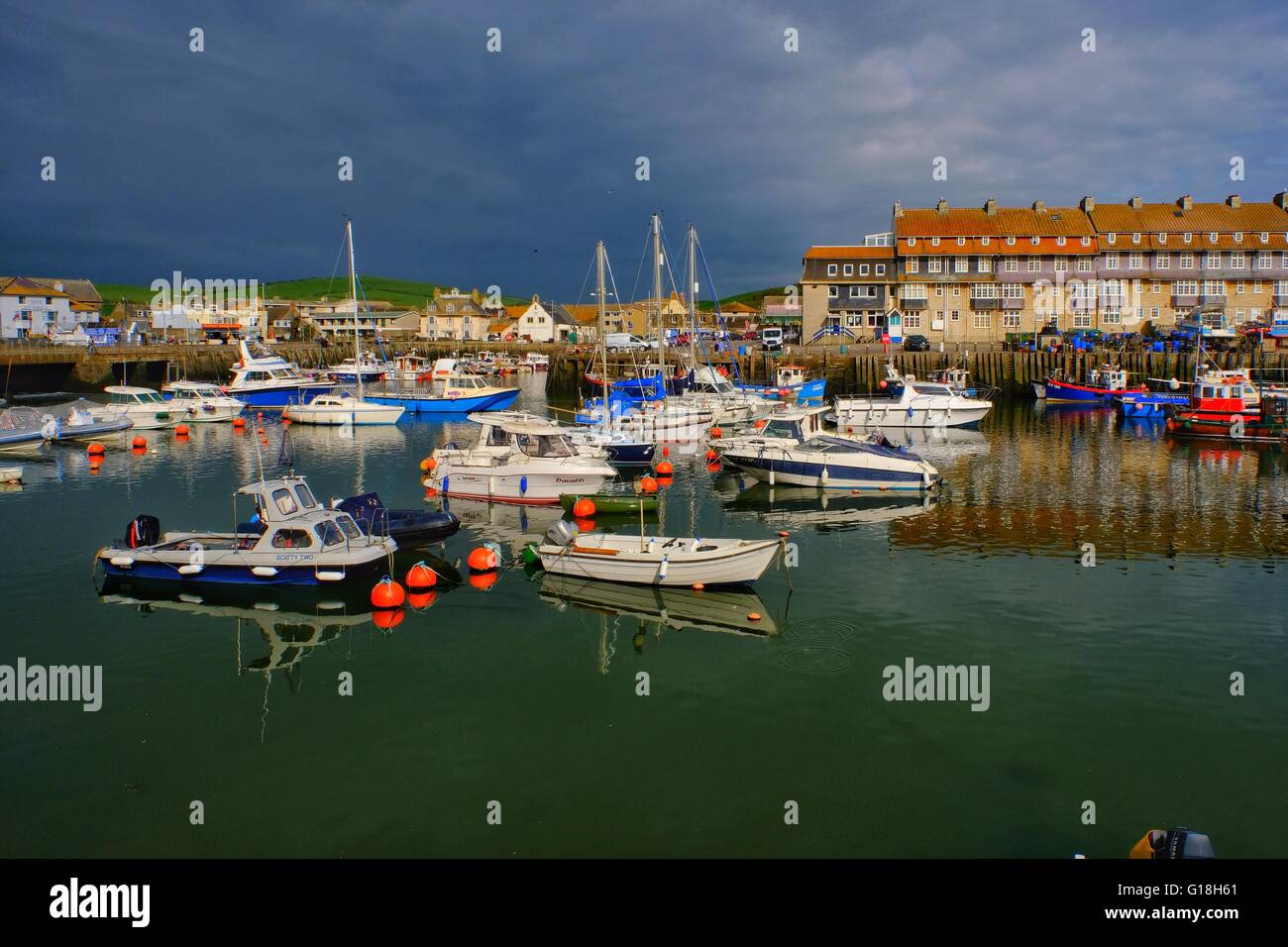 West Bay, Dorset, UK. 10 May 2016. West Bay harbour is bathed in evening sunshine as rain clouds gather bringing further rain to the south west. Credit:  Tom Corban/Alamy Live News Stock Photo