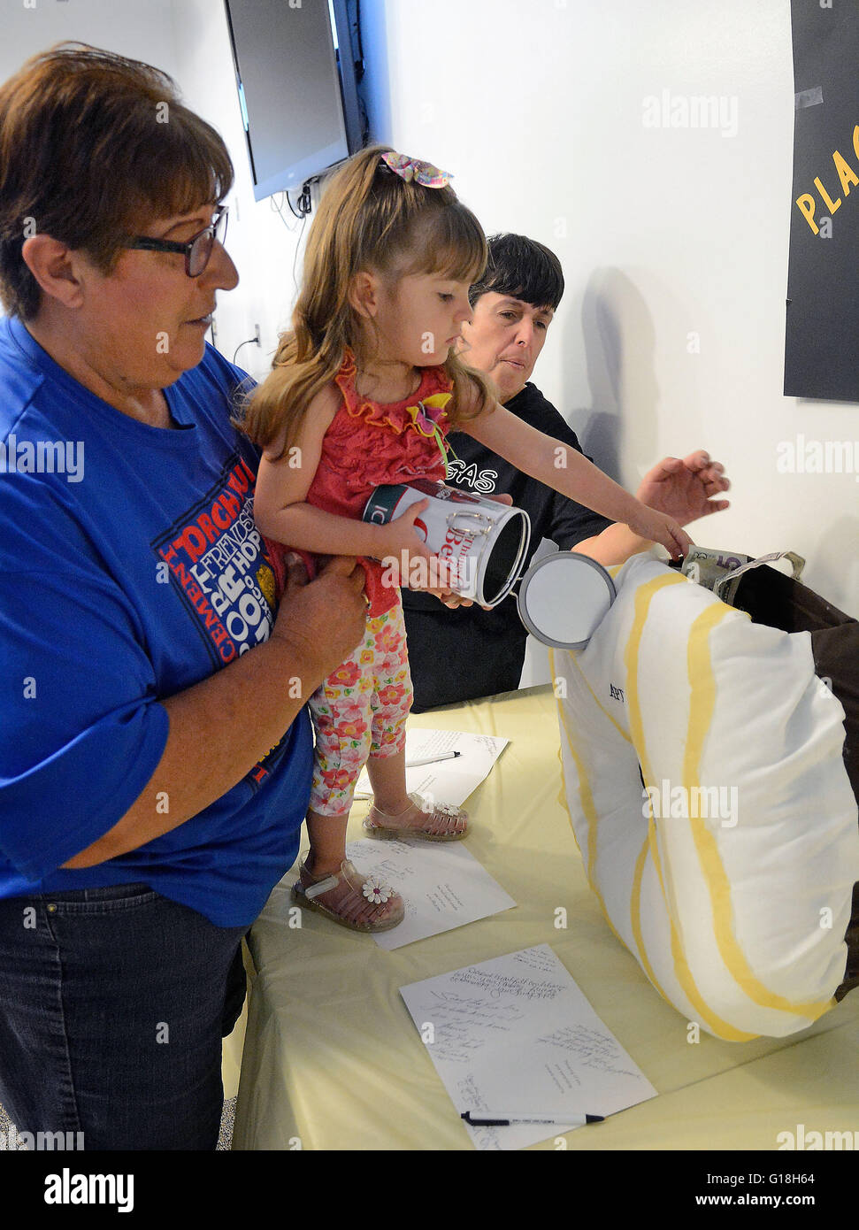 Albuquerque, NM, USA. 10th May, 2016. Priscilla Lopez holds her niece Cecilia Molina-2 and Patricia Lopez helps as she puts money into the giant donut at the Coffee with a Cop for Ashlynne Mike at the SouthWest Substation Tuesday morning. Tuesday, May 10, 2016. © Jim Thompson/Albuquerque Journal/ZUMA Wire/Alamy Live News Stock Photo