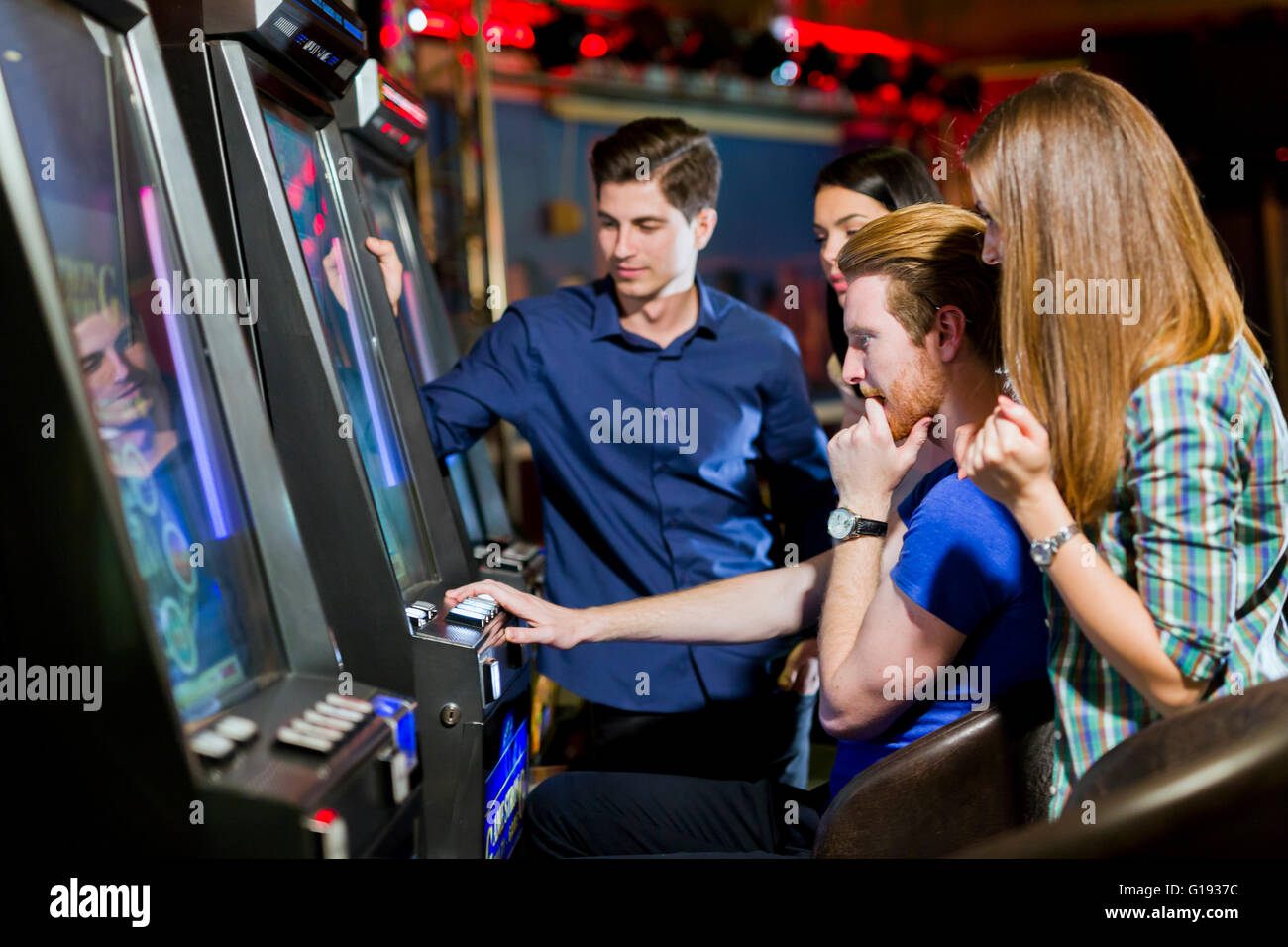 Young group of people gambling in a casino playing slot and various machines Stock Photo