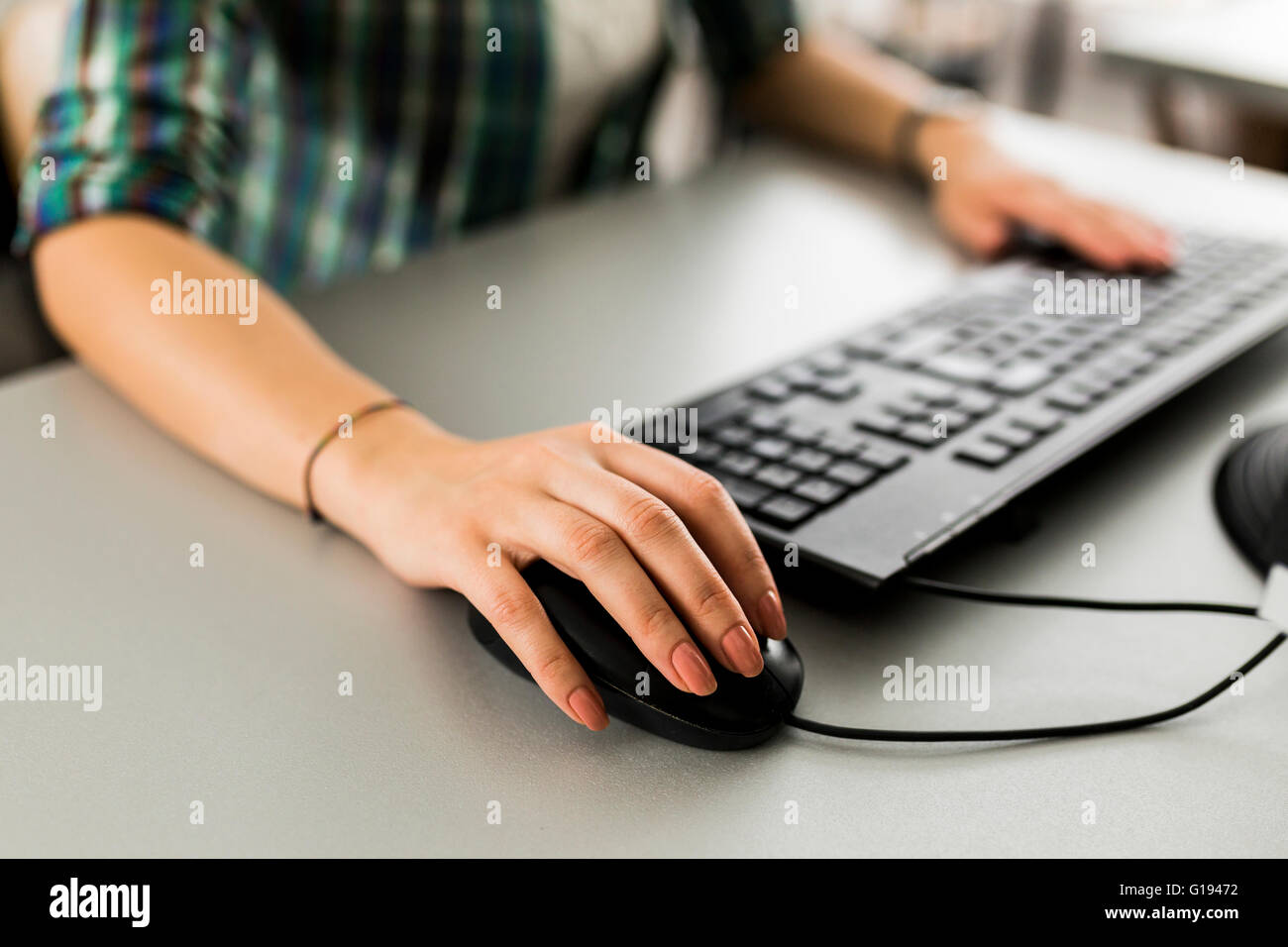 Close up of a woman using a computer keyboard and a mouse Stock Photo
