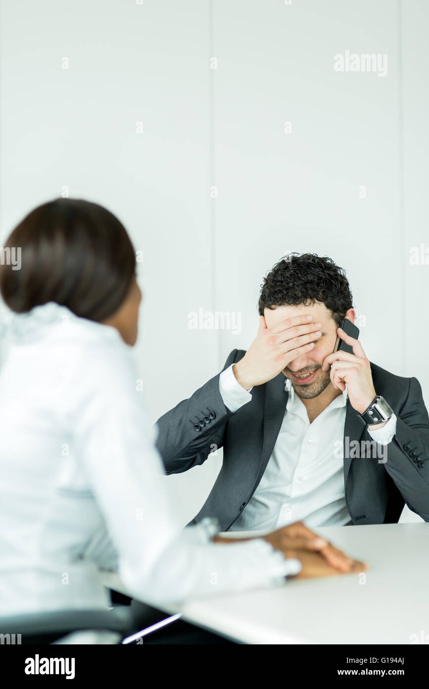 Businessman receiving bad news on the phone having a headache over the problems Stock Photo
