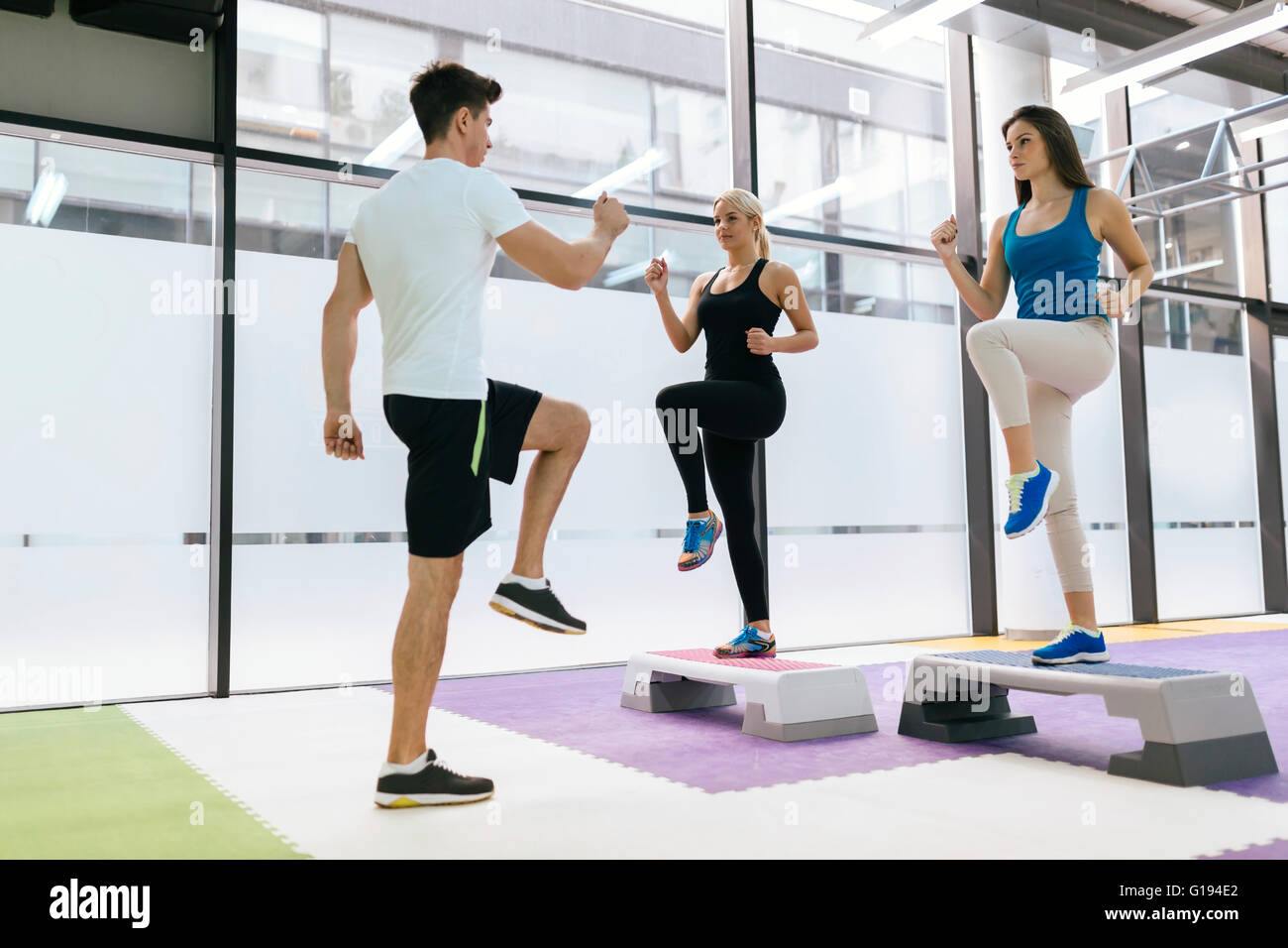 Personal trainer exercising with aerobics trainees in fitness club Stock Photo