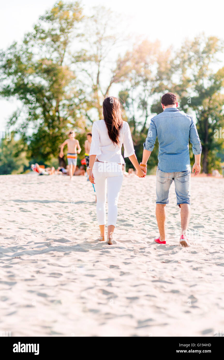 Couple holding hands and walking on a sandy beach Stock Photo