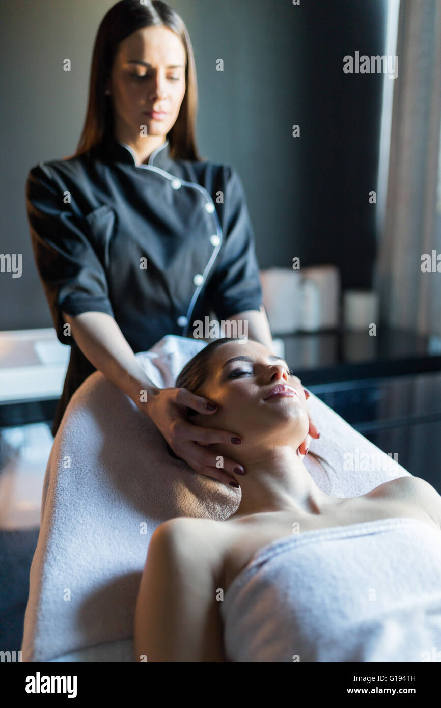 Masseur treating face of a beautiful, young woman lying on the massage table Stock Photo